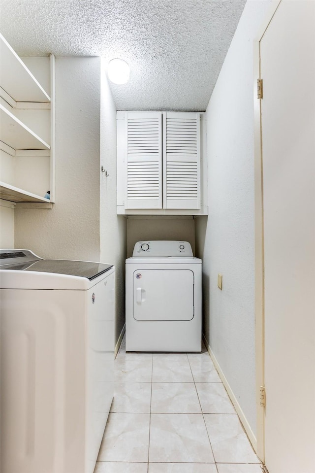 laundry room with a textured ceiling, laundry area, light tile patterned flooring, and independent washer and dryer