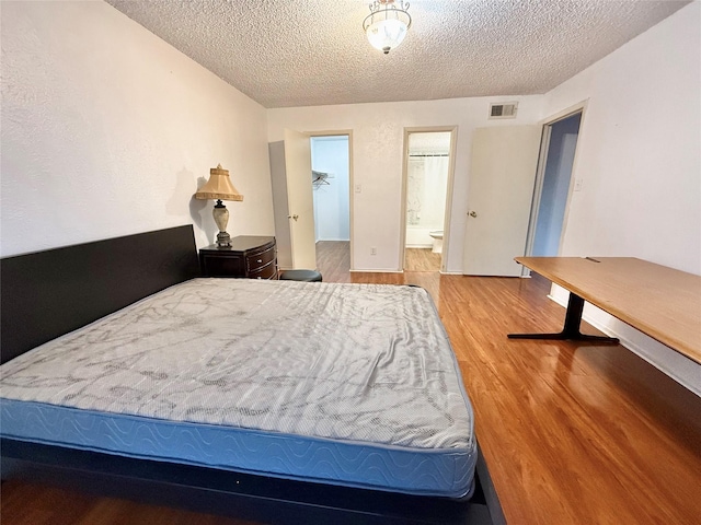 919 S Weatherred Dr Unit 211, Richardson, TX 75080 - bedroom with a textured ceiling, wood finished floors, and ensuite bathroom