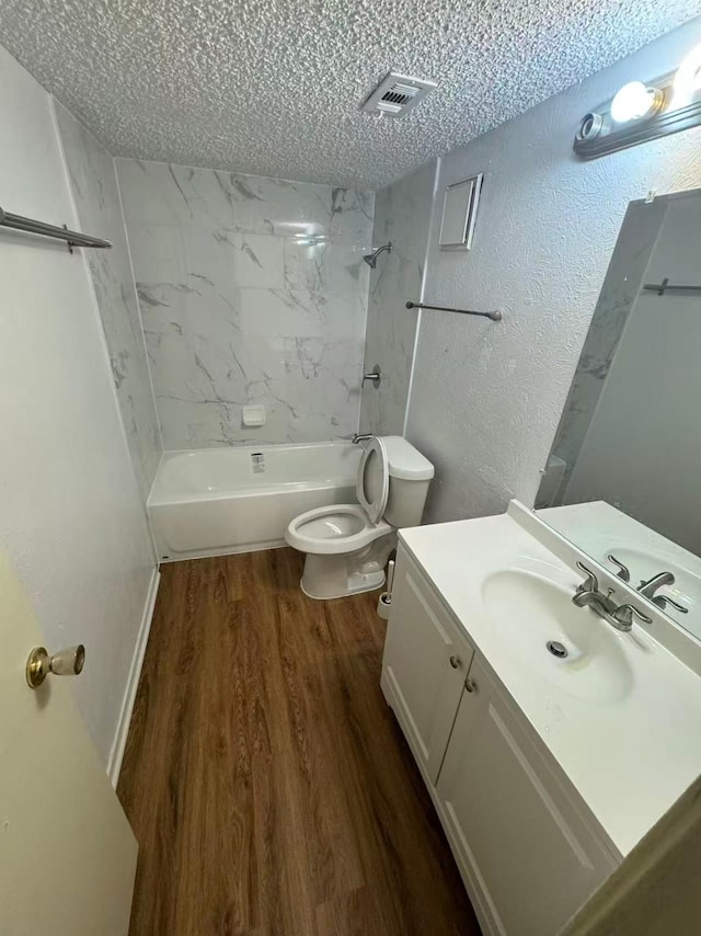 bathroom with toilet, a textured ceiling, shower / washtub combination, and wood finished floors
