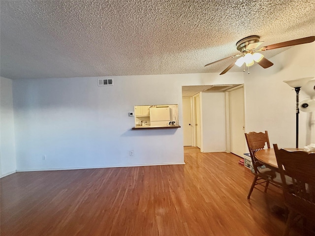 919 S Weatherred Dr Unit 211, Richardson, TX 75080 - unfurnished living room featuring a textured ceiling, a ceiling fan, wood finished floors, and baseboards