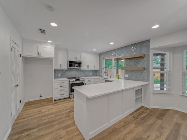 kitchen with open shelves, appliances with stainless steel finishes, a sink, light countertops, and visible vents