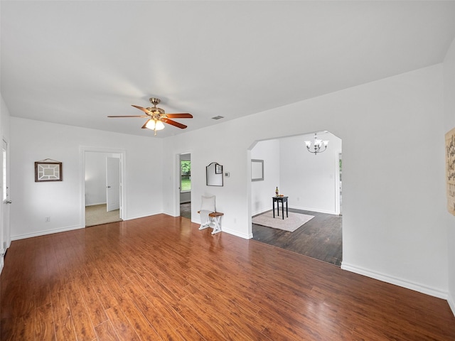 unfurnished living room featuring visible vents, wood finished floors, baseboards, arched walkways, and ceiling fan with notable chandelier