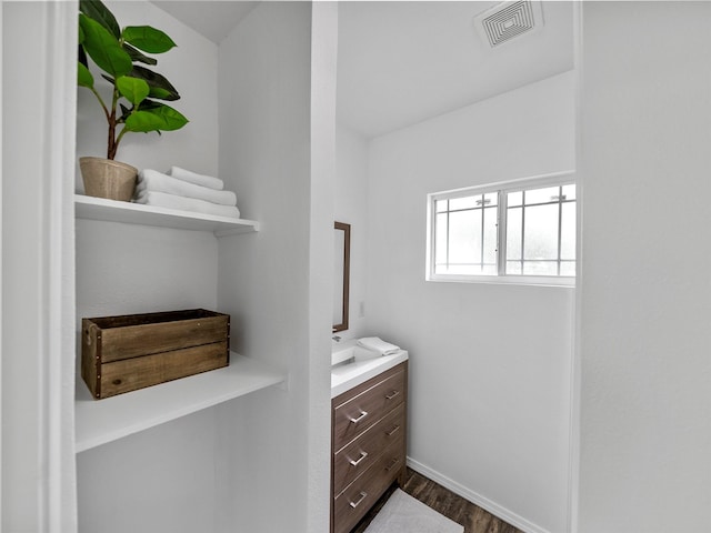 bathroom with baseboards, visible vents, wood finished floors, and vanity