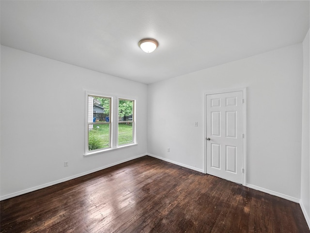 spare room featuring baseboards and dark wood-style flooring