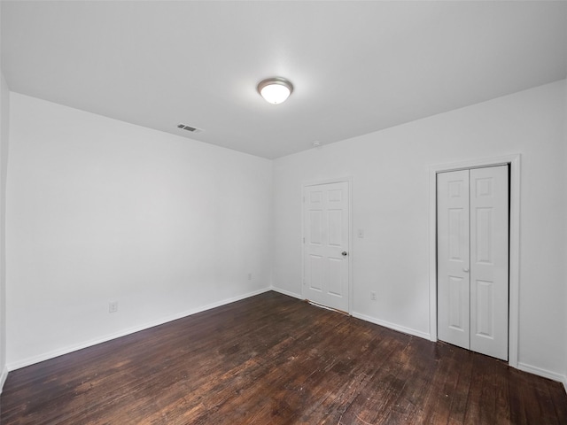 spare room featuring baseboards, visible vents, and dark wood finished floors