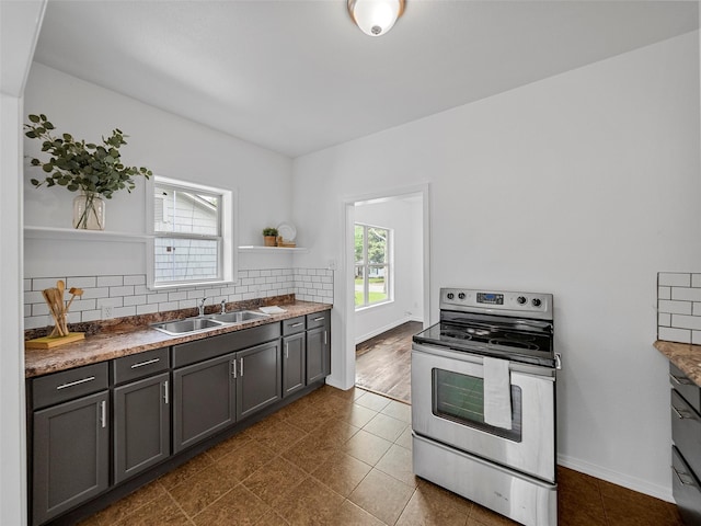 kitchen featuring open shelves, electric range, dark tile patterned flooring, a sink, and backsplash