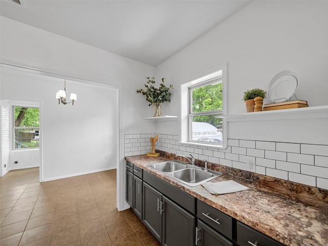 kitchen featuring open shelves, a sink, a chandelier, baseboards, and backsplash
