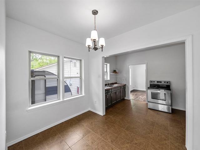 kitchen featuring baseboards, a sink, stainless steel range with electric stovetop, and a chandelier