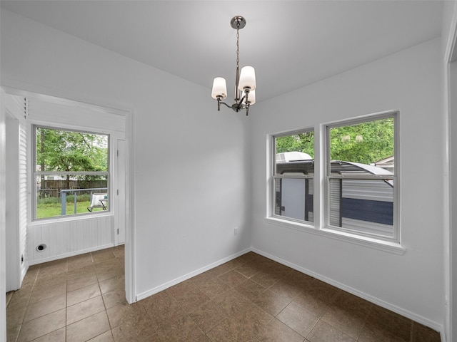 tiled spare room with baseboards and a chandelier