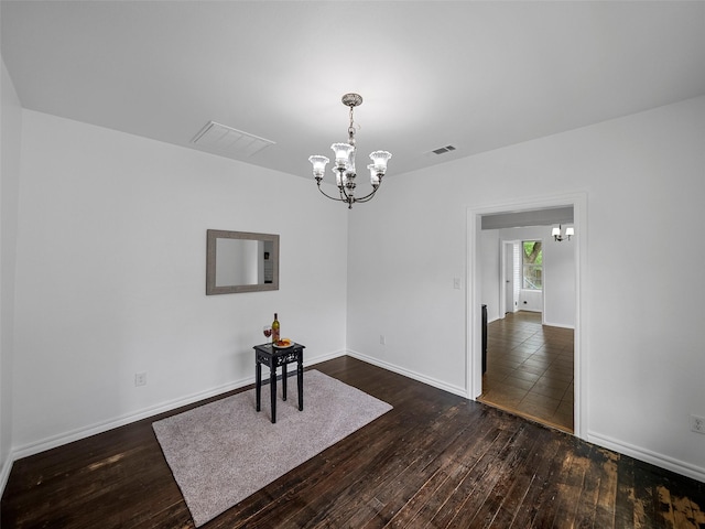 unfurnished dining area featuring an inviting chandelier, baseboards, dark wood-style floors, and visible vents