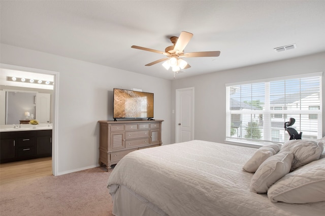 bedroom with light carpet, a sink, ensuite bath, baseboards, and visible vents