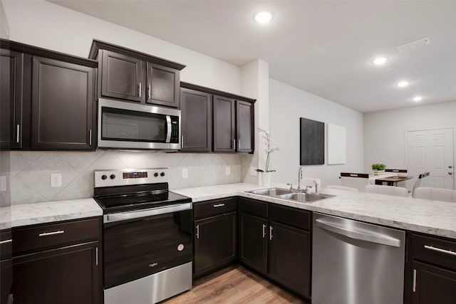 kitchen featuring decorative backsplash, a sink, light wood finished floors, stainless steel appliances, and recessed lighting