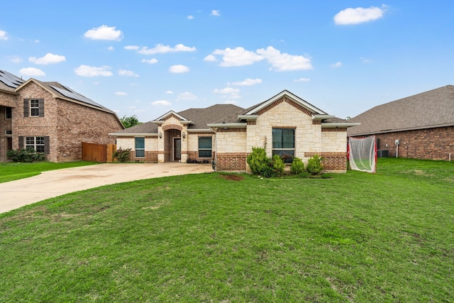 ranch-style home with brick siding, a front lawn, roof with shingles, and fence