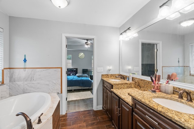 ensuite bathroom with double vanity, a bath, wood finished floors, a sink, and ensuite bathroom