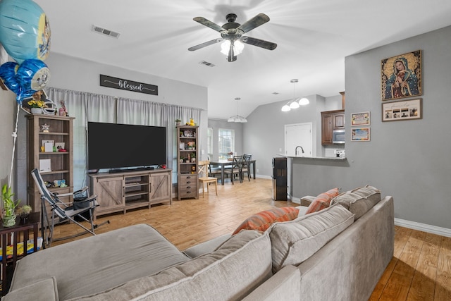 living room featuring baseboards, ceiling fan, wood finished floors, and lofted ceiling