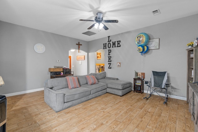 living area with visible vents, a ceiling fan, arched walkways, and light wood-type flooring