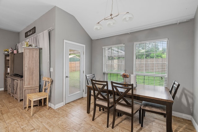 dining room featuring light wood-style floors, baseboards, vaulted ceiling, and a notable chandelier