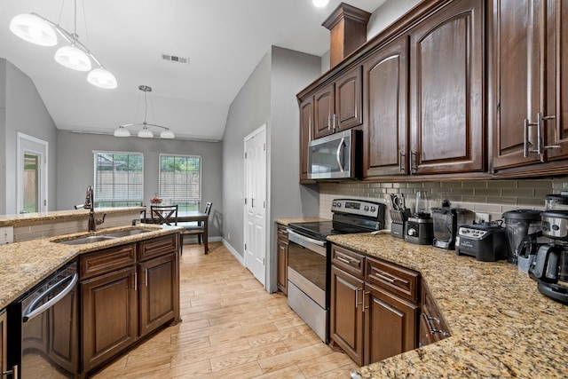 kitchen with visible vents, a sink, appliances with stainless steel finishes, backsplash, and vaulted ceiling