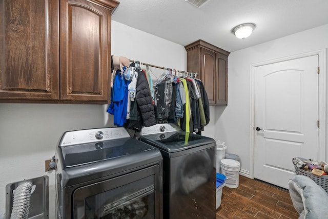 washroom with baseboards, cabinet space, washing machine and dryer, and dark wood-style floors