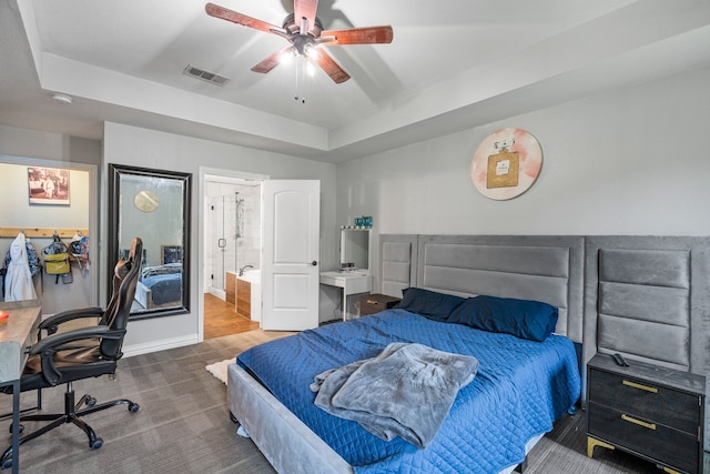 carpeted bedroom with visible vents, baseboards, a raised ceiling, connected bathroom, and a ceiling fan
