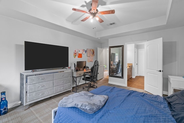 bedroom featuring visible vents, baseboards, ceiling fan, and a tray ceiling