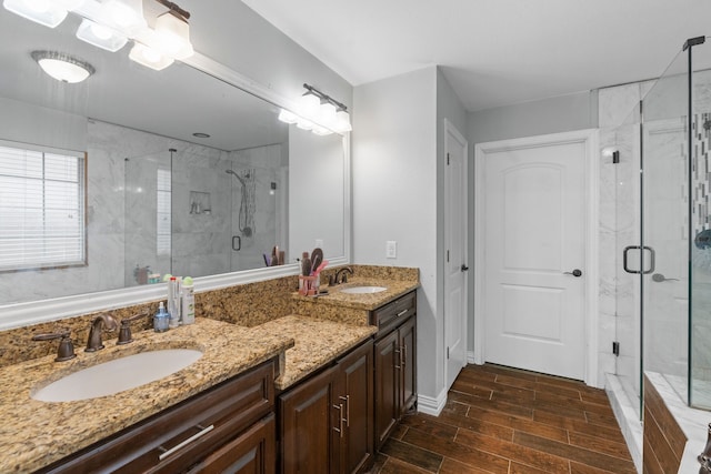 full bathroom with double vanity, a sink, a stall shower, and wood tiled floor