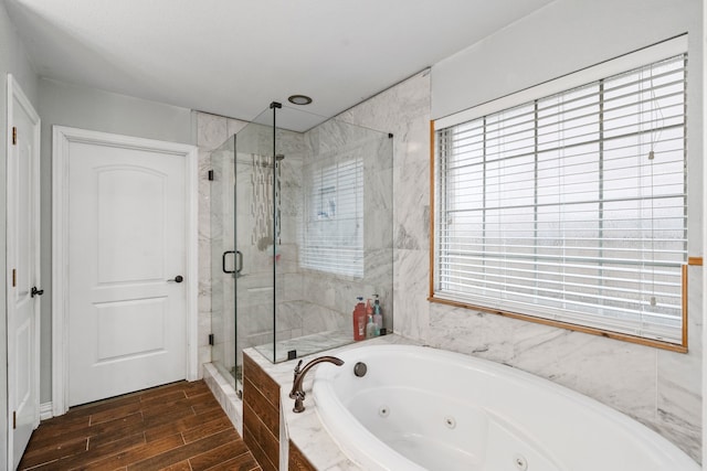 bathroom featuring wood finished floors, a marble finish shower, and a jetted tub