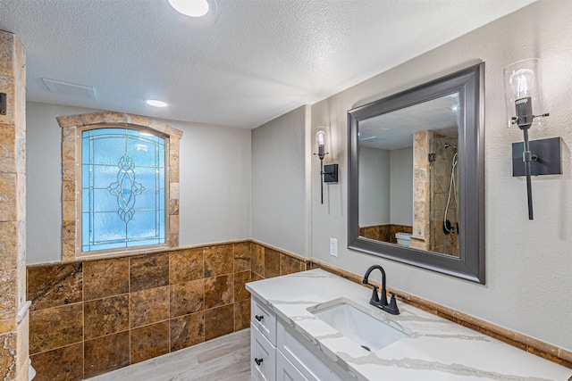 1603 Hawthorne Dr, Arlington, TX 76012 - bathroom featuring a textured ceiling, tile walls, wainscoting, and a shower