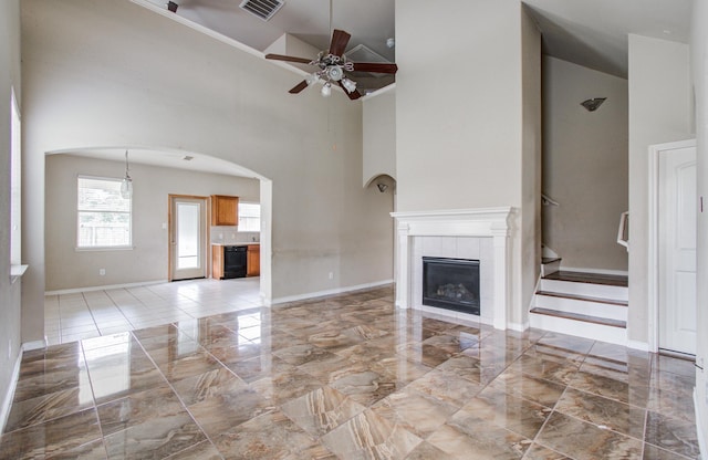 21107 Pine Monte Ridge Ln, Katy, TX 77449 - unfurnished living room with marble finish floor, ceiling fan, high vaulted ceiling, a tile fireplace, and arched walkways