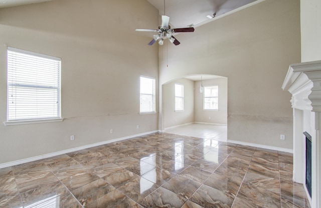 21107 Pine Monte Ridge Ln, Katy, TX 77449 - unfurnished living room featuring a ceiling fan, a towering ceiling, arched walkways, baseboards, and marble finish floor