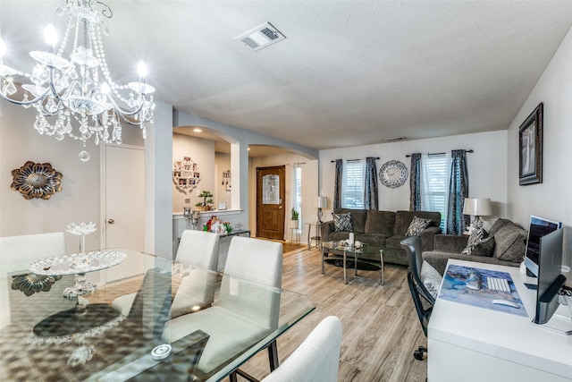 9813 Jericho Ln, Fort Worth, TX 76108 - dining room with arched walkways, light wood finished floors, a textured ceiling, and a chandelier