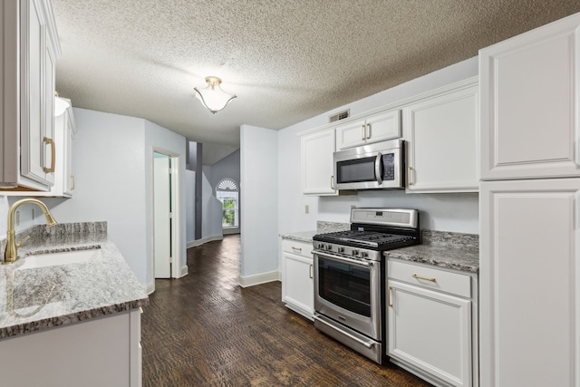 kitchen featuring visible vents, dark wood finished floors, a sink, stainless steel appliances, and white cabinetry