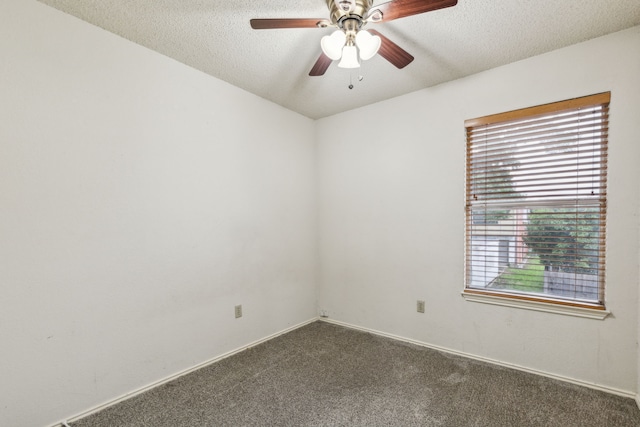 spare room with baseboards, ceiling fan, dark colored carpet, and a textured ceiling