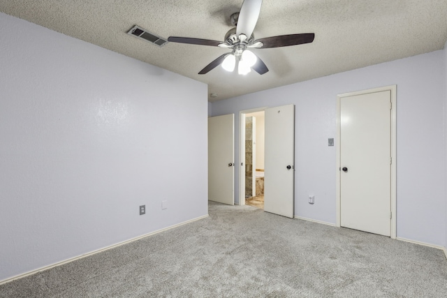 unfurnished bedroom featuring visible vents, carpet floors, baseboards, ensuite bathroom, and a textured ceiling
