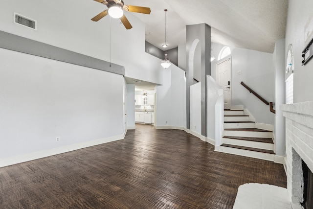 unfurnished living room featuring visible vents, a ceiling fan, stairs, and high vaulted ceiling