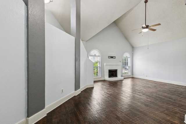 unfurnished living room with wood finished floors, baseboards, high vaulted ceiling, a fireplace with raised hearth, and a ceiling fan