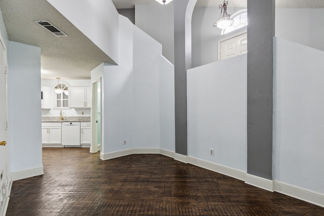 interior space featuring dark wood-style flooring, a high ceiling, visible vents, and baseboards