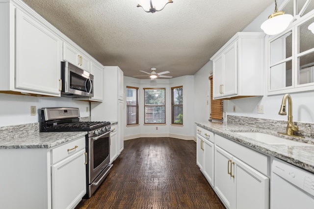 kitchen featuring a ceiling fan, dark wood-style flooring, white cabinets, a sink, and stainless steel appliances