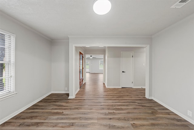 unfurnished room featuring crown molding, baseboards, visible vents, and wood finished floors