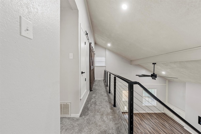 hall with a barn door, baseboards, an upstairs landing, vaulted ceiling, and visible vents