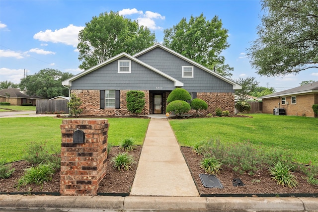 view of front of property featuring fence, a front yard, and brick siding