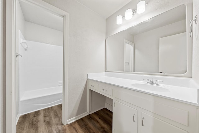 bathroom with baseboards, wood finished floors, shower / bathing tub combination, and vanity