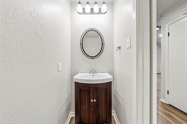 bathroom featuring vanity, a textured wall, and wood finished floors