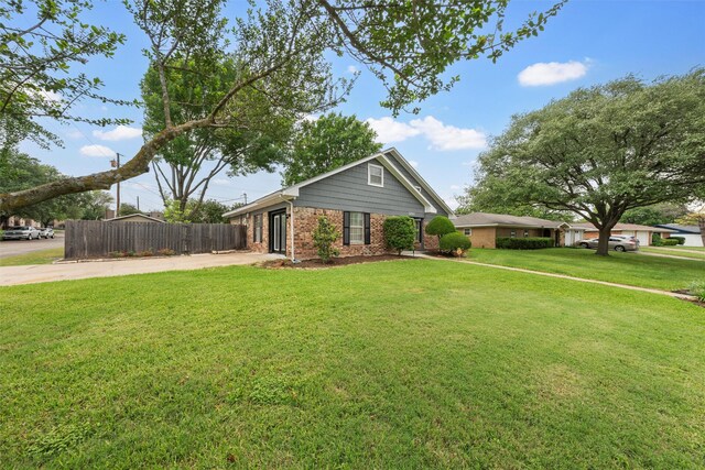 view of front of home featuring fence, a front yard, driveway, and brick siding