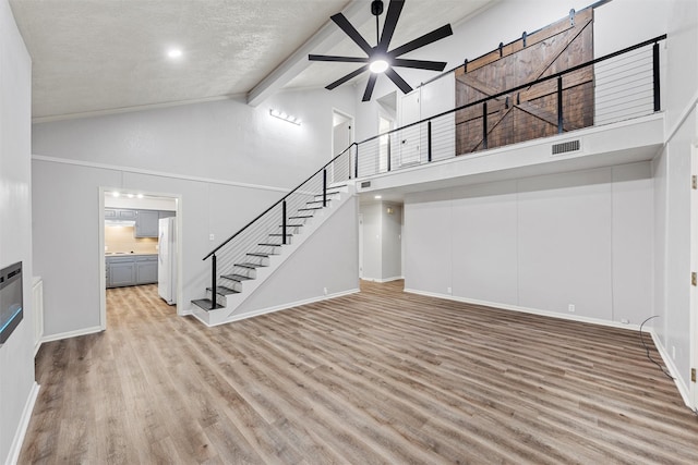 unfurnished living room featuring stairs, beamed ceiling, high vaulted ceiling, a ceiling fan, and light wood-style flooring