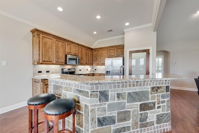 kitchen with brown cabinetry, arched walkways, baseboards, and stainless steel appliances