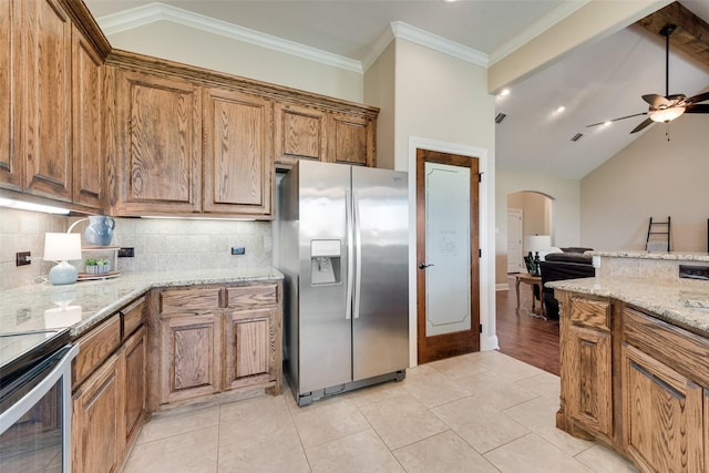 kitchen featuring brown cabinets, stainless steel appliances, ceiling fan, and backsplash