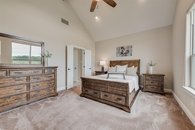 bedroom with high vaulted ceiling, light colored carpet, multiple windows, and visible vents