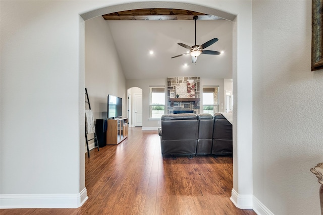 living area featuring arched walkways, ceiling fan, baseboards, and wood finished floors