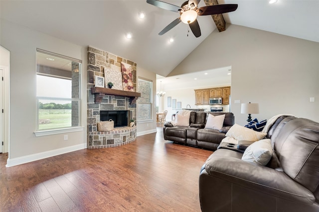 living area with ceiling fan, a stone fireplace, wood finished floors, high vaulted ceiling, and beamed ceiling
